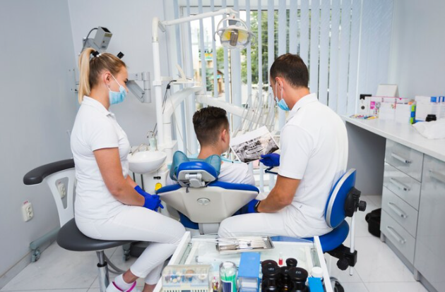 Dentist talking to a patient together with his assistant, Holistic Dentistry - Gentle Touch